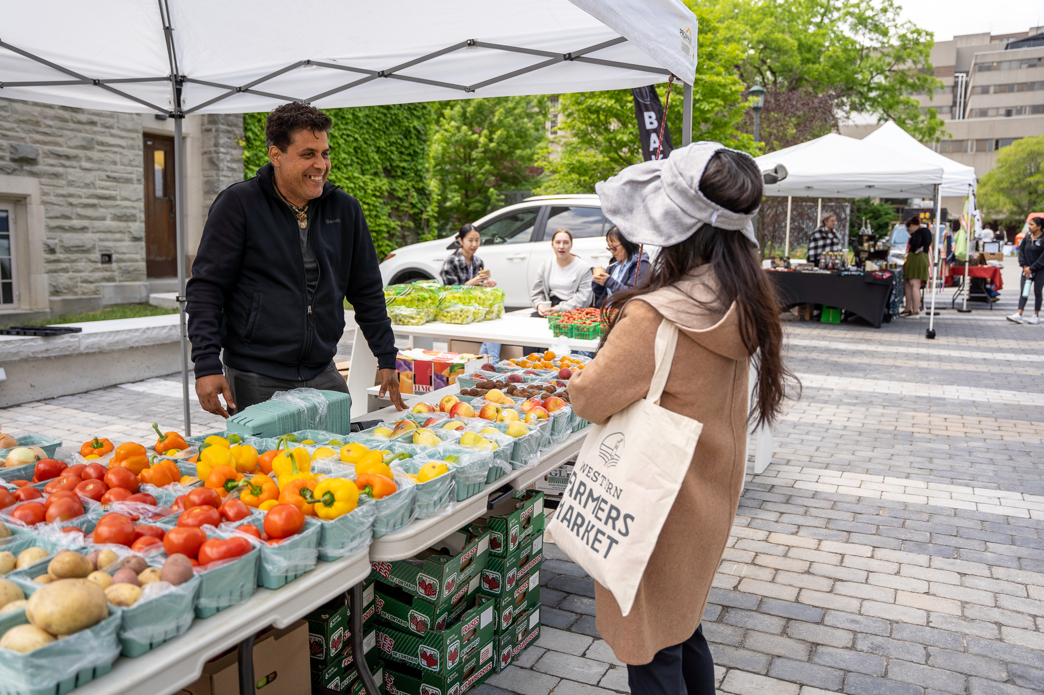 Woman chats with male vendor about produce at Farmers Market.