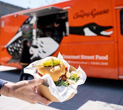 A chicken sandwich in front of the Angry Goose Food Truck