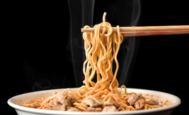 A photo of ramen noodles being pulled out of a bowl by chopsticks